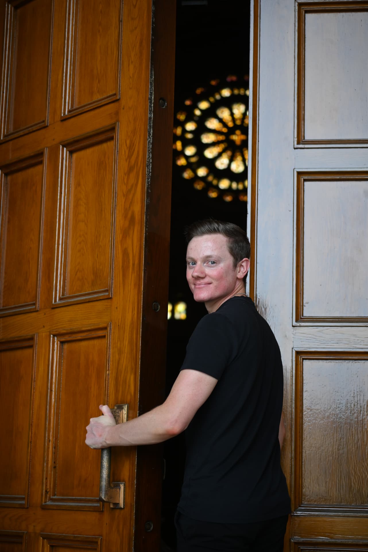 Grady J. Connolly opening a basilica door beneath a rose window